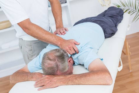 Physiotherapist doing neck massage to his patient in medical office