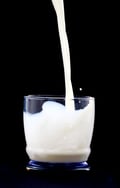 milk being poured in a glass over a black background-1